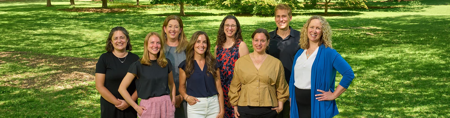 Orion Initiative team members stand outside on a sunny day with green grass in the background