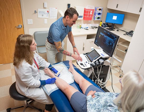 MiniFellowship An academic physician uses an ultrasound on a patient's ankle while Dr. Kroll views the monitor