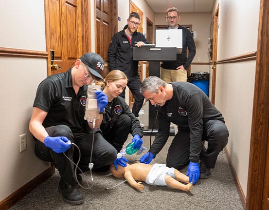Emergency medical technicians training on a pediatric manikin