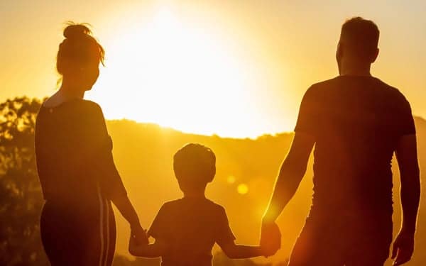 family-7392843_1280 A family holds hands with their backs turned to the camera with a sunset in the background